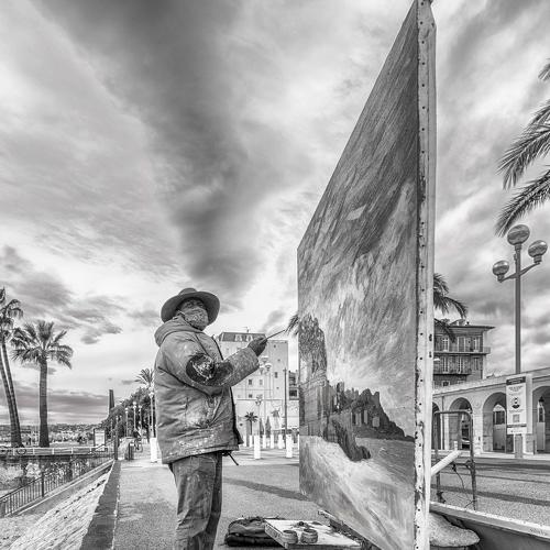 The artist is painting on the street