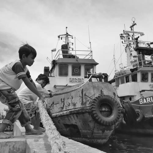Two children trying to tow a ship