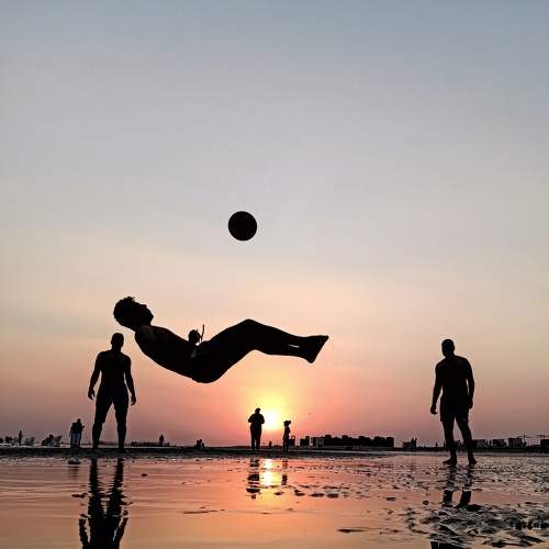 Some friends enjoy playing soccer at the seaside