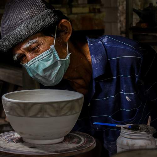 An old man finishes the job of making bowls
