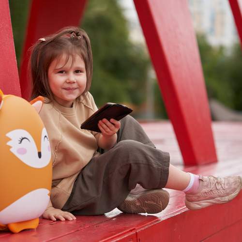 A little smiling girl with a smartphone in her hand.