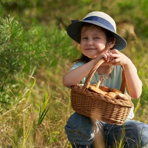 A girl in a straw hat with a basket of mushrooms.
