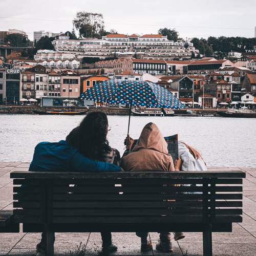 Family sitting on a bench, hiding from the rain.