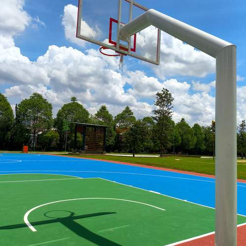 A basketball hoop on a blue court with trees in the background