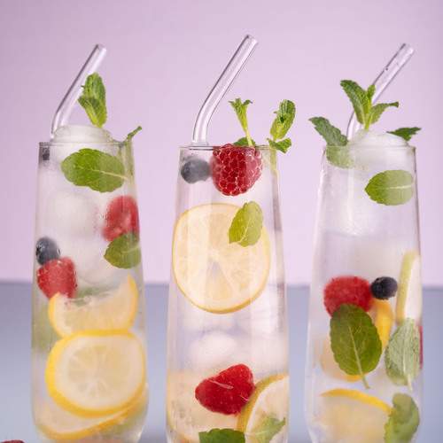 glasses of water with lemon, raspberry, and blueberry slices on a light background