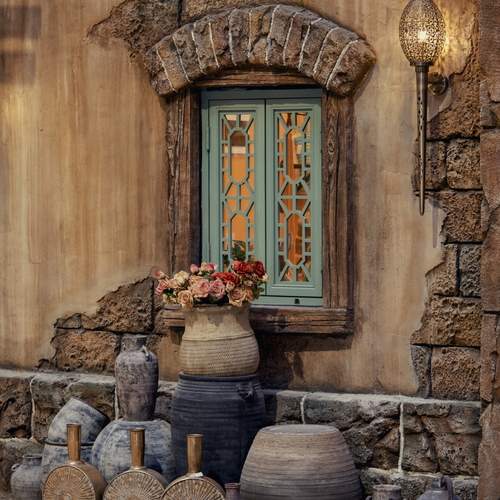 A sturdy stone wall featuring a window alongside an array of vases