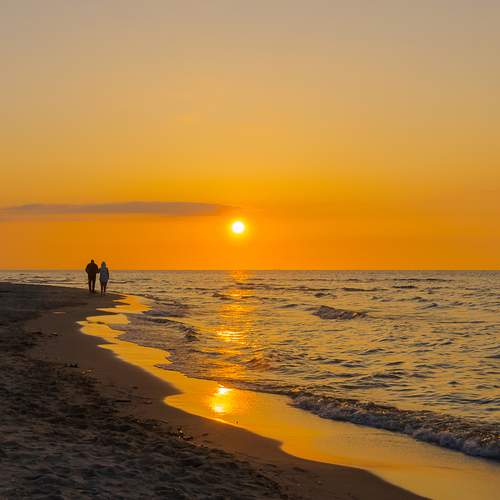 A walk on the beach towards the sun.