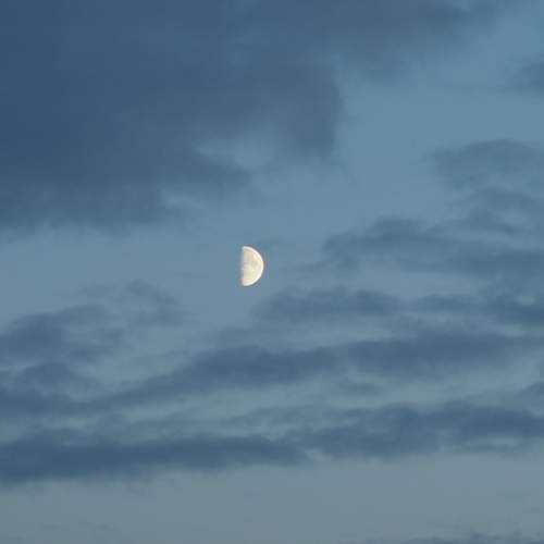 Moon in the blue sky with clouds background.
