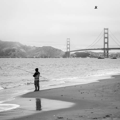 Fisherman on Baker Beach with the Golden Gate Bridge in the background