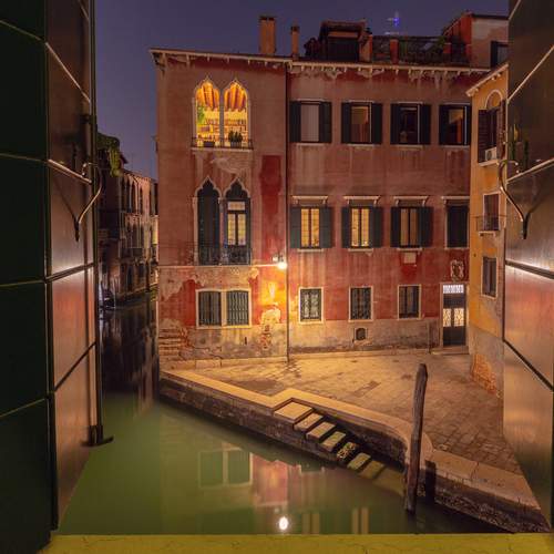 View of a Venetian canal through a window at night.