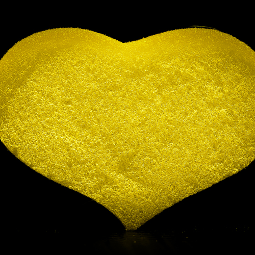 Yellow foam sponge for a heart-shaped shower on a black background.