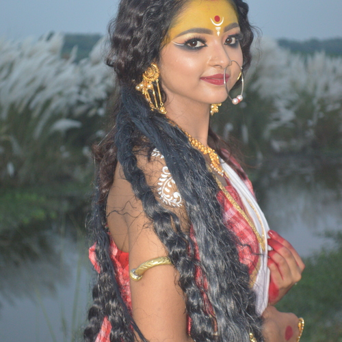 West Bengal Festival Durga Puja A girl dressed as Durga stands next to a cashew tree.