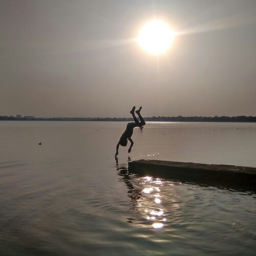 small boy div at water at time of sun set