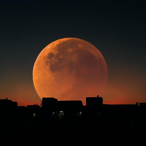 Red moon behind the building