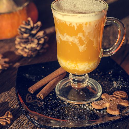 natural pumpkin juice, a composition of a glass of juice on a pumpkin background, on a wooden table in warm sunlight