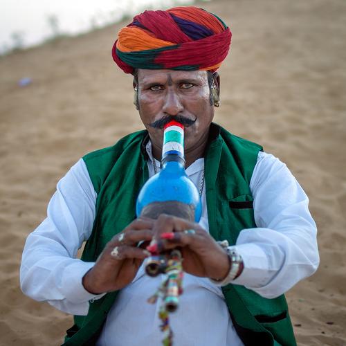 A snake charmer playing his murli in the desert of Pushkar