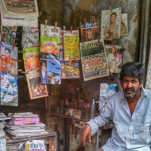 Shabbily dressed man selling newspapers