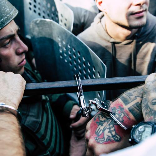 A protester is handcuffed to a fence.