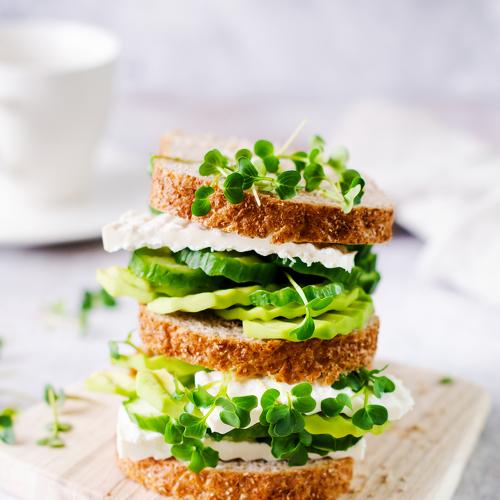 Avocado, cucumber and feta cheese sandwich decorated with micro-greens.