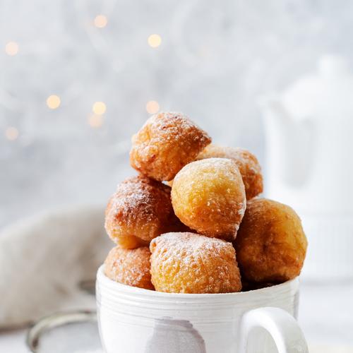 Little Donuts with icing sugar in a vintage ceramic cup.