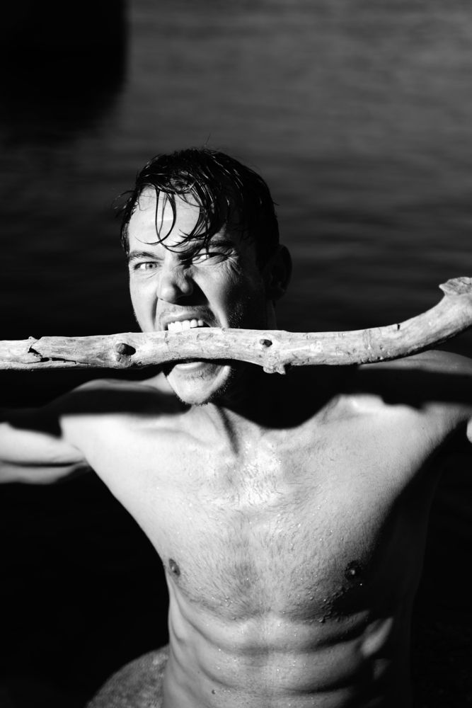 Portrait of male model in lake biting branch